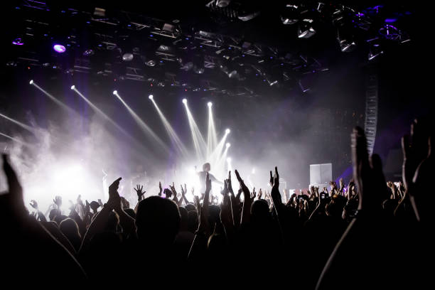 istock Crowd on music show, happy people with raised hands. White stage light. Frontman on stage. 1141666315