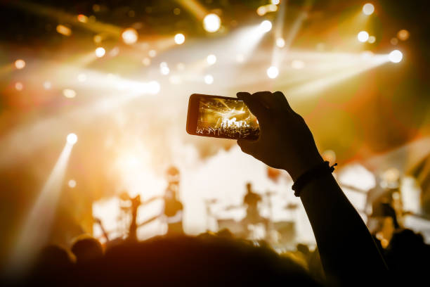 istock Filming a concert on mobile phone camera, yellow light 1141666327