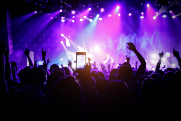 istock Smartphone in hand at a concert, purple light from stage 1141666338