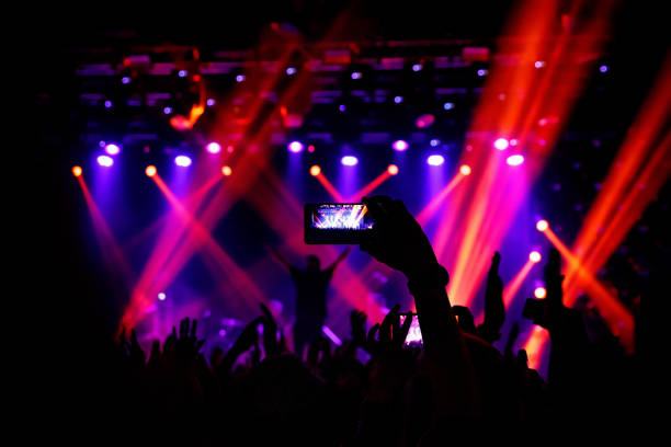 istock Smartphone in hand at a concert, purple light from stage 1141666351