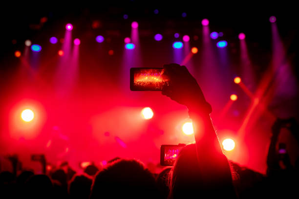 istock Smartphone in hand at a concert, red light from stage 1141666360