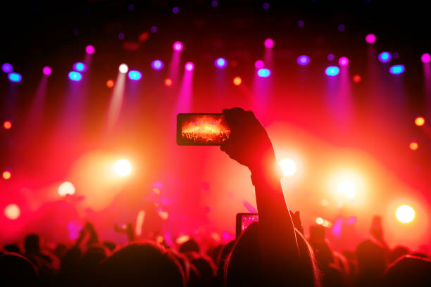 istock Smartphone in hand at a concert, red light from stage 1141666363