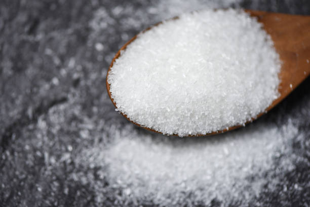 MSG / Monosodium glutamate on wooden spoon with dark background