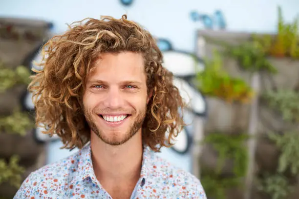 Outdoor Head And Shoulders Portrait Of Smiling Young Man