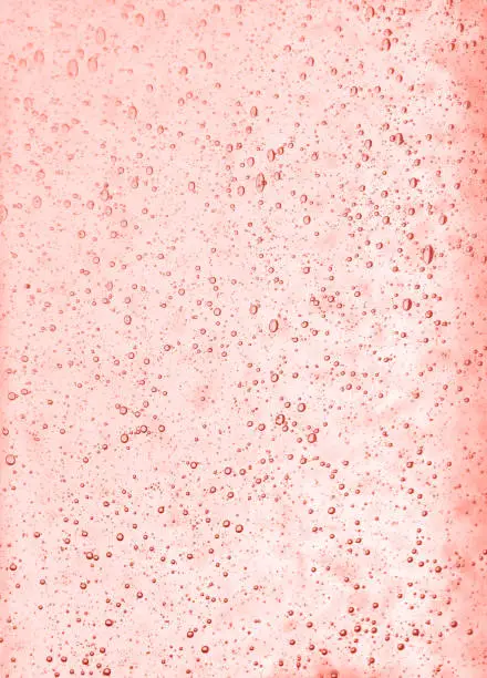 Background texture of solid transparent coral color toned pink glass with pattern of air bubbles, close up