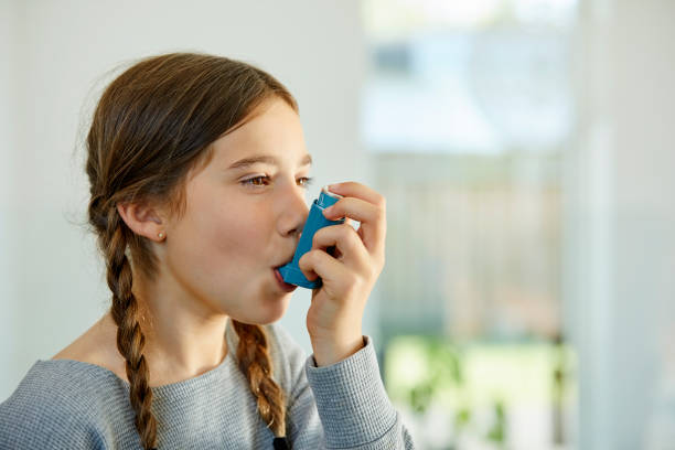 nahaufnahme des mädchens mit asthma-inhalator zu hause - asthmainhalator stock-fotos und bilder