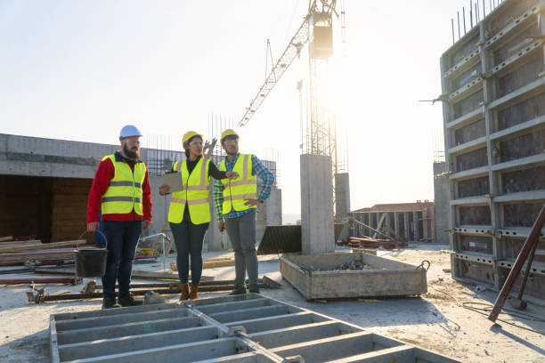 istock WS, Meeting of a Confident Female Architect, A Project Manager and a Construction Workers Discussing and Working Together at Construction site of a Residential Building on a Bright Sunny Day Using Architectural Drawings and a Digital Tablet 1141670329