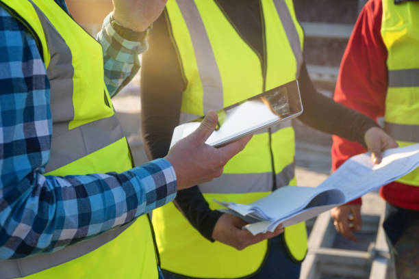 istock CU, Meeting of a Female Architect, A Project Manager Holding a Digital Tablet, and a Construction Workers Discussing and Working Together at Construction site of a Residential Building on a Bright Sunny Day. 1141670385
