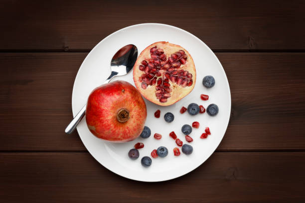 blueberries and pomegranate with a silver spoon on white plate