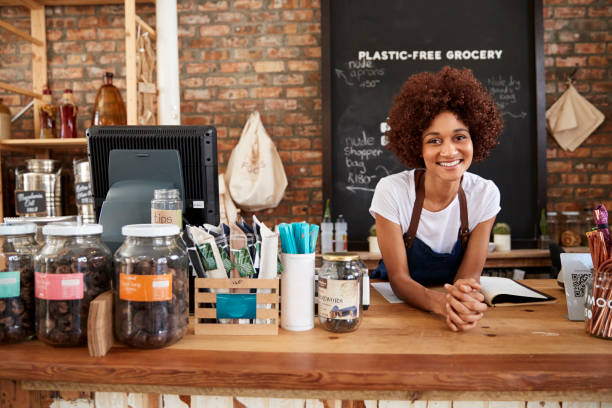 Portrait Of Female Owner Of Sustainable Plastic Free Grocery Store Behind Sales Desk Portrait Of Female Owner Of Sustainable Plastic Free Grocery Store Behind Sales Desk social responsibility photos stock pictures, royalty-free photos & images