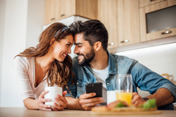 istock Happy couple eating breakfast using phone 1141676906