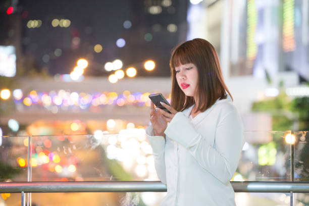 istock Young Asian Businesswoman Using Phone at Night 1141678454