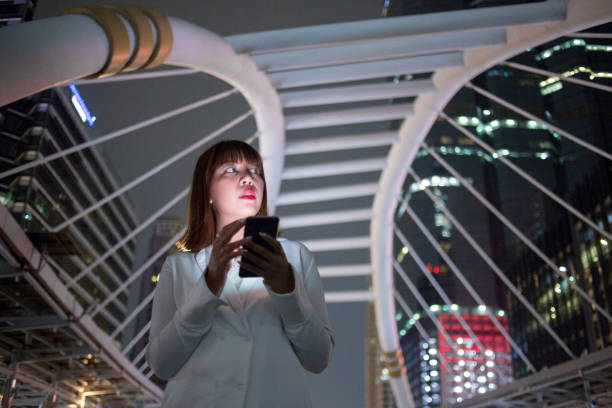 istock Young Asian Businesswoman Using Phone at Night 1141678492