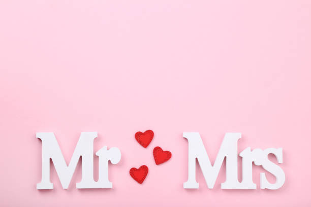 istock White letters Mr and Mrs with red hearts on pink background 1141678512