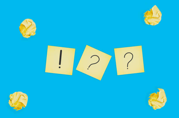 istock Three square paper sheets with handwritten question and exclamation marks near lot of scattered crumpled paper balls on blue table. Top view. Business concept 1141680162