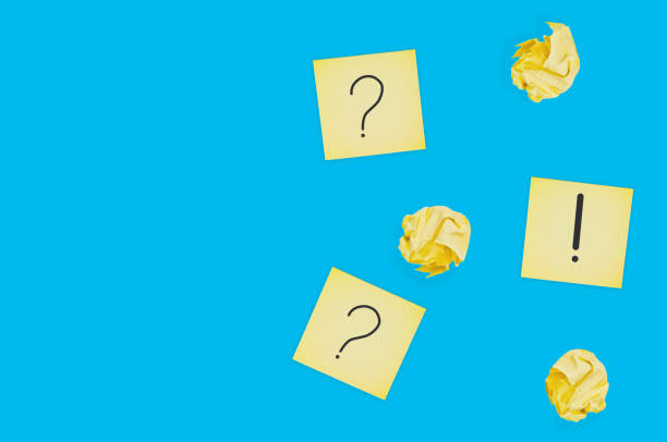 istock Three square paper sheets with handwritten question and exclamation marks near lot of scattered crumpled paper balls on blue table. Top view. Business concept. Copy space 1141680169
