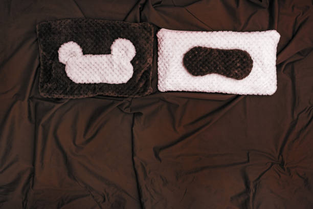 istock Soft pillow and sleep mask on dark crumpled sheet. Two seats in bed. Top  view. Flat lay. 1141680384