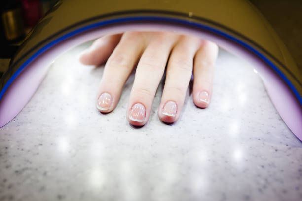 istock Woman hand inside lamp for nails on table close up. UV lamp for drying nails with gel method. nails dried in the lamp 1141684254
