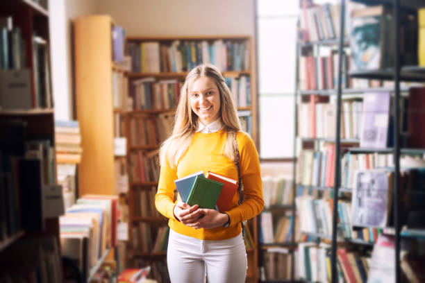 istock Young smiling student holding a book in the library. 1141685533