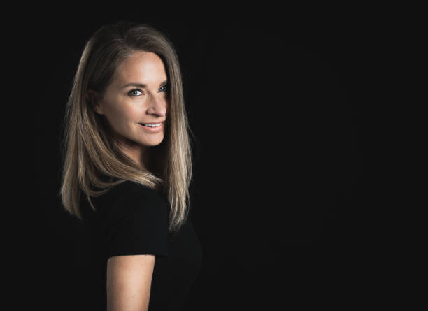 istock Beautiful middle aged blond woman on black background 1141685706