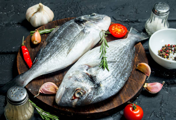istock Raw sea fish dorado with spices and vegetables. 1141688516