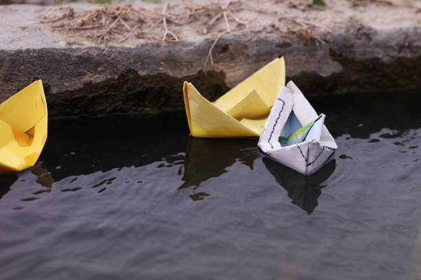 istock Flowing paper boat in to water 1141690664