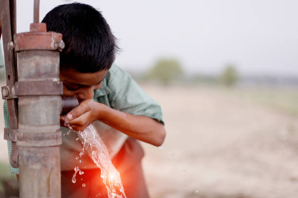 Thirsty child drinking water on water pump.