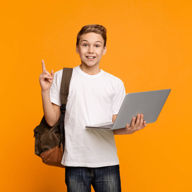 istock Cheerful boy holding laptop surprised with idea pointing finger up 1141692659