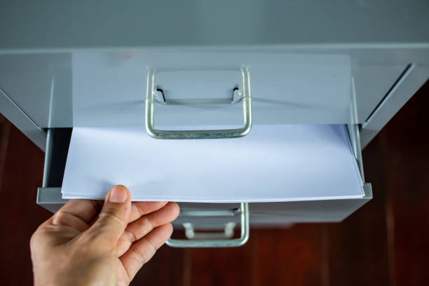 istock Woman's hand pick up white papers for write letter, Filing cabinet with open drawer, Silver grey metal colour, Administration and storage, Close up shot, Selective focus, Stationery, Business concept 1141692786