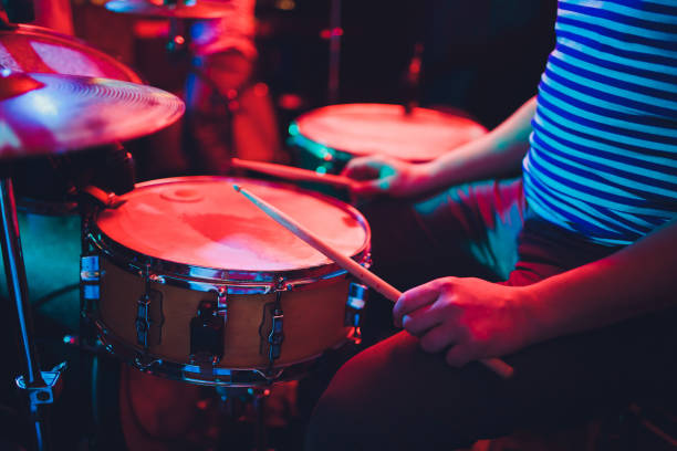 istock man plays musical percussion instrument with sticks closeup on a black background, a musical concept with the working drum, beautiful lighting on the stage. 1141693739