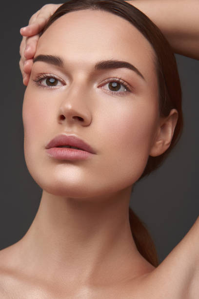 istock Charming young woman with natural makeup keeping hand above her head 1141694633
