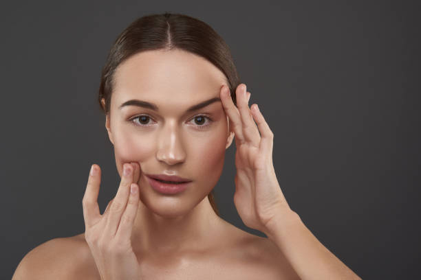 istock Beautiful young woman with natural makeup touching her face 1141694641