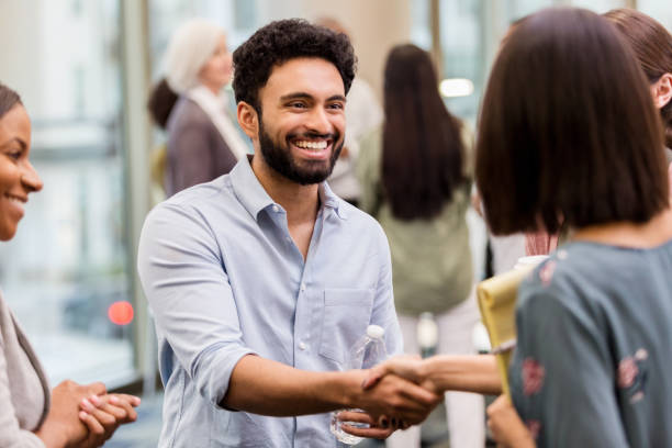 A mixed race man greets his boss Before the conference, a young adult greets his boss with a smile. casual handshake stock pictures, royalty-free photos & images