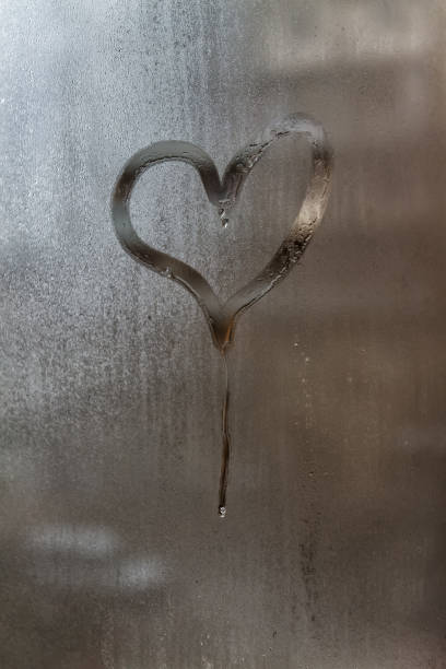 Drip in the shape of a heart on a misted window-glass. Close-up. Background stock photo