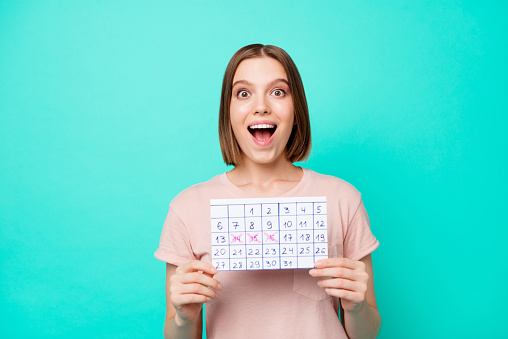Close up photo beautiful her she lady cute arms hands hold calendar not believe it is hightime weekend vacation open mouth toothy beaming smile wear casual t-shirt isolated teal turquoise background.