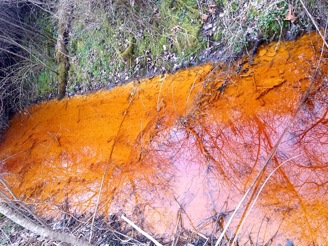 A stream is bright orange with run-off from acid mine drainage