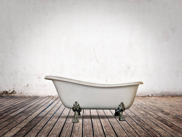A clawfoot bathtub, sink and mirror in a wallpapered bathroom