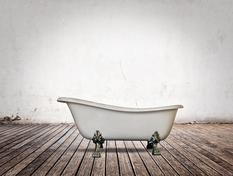 vintage bathtub in bathroom with white wall and wood floor