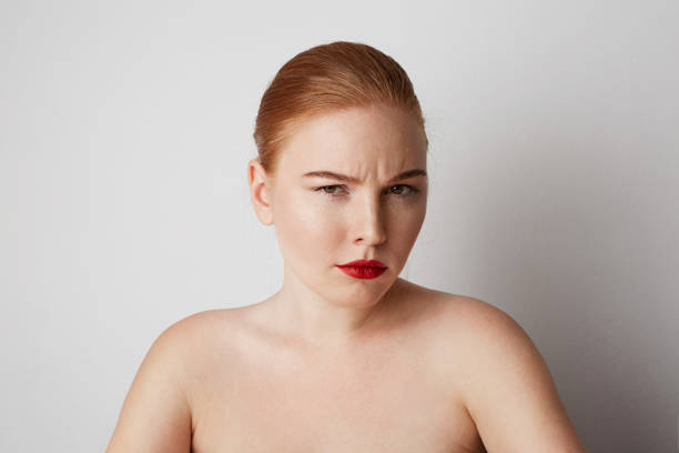 istock Young redhead female model with light nude make-up posing over white background. 1141698628