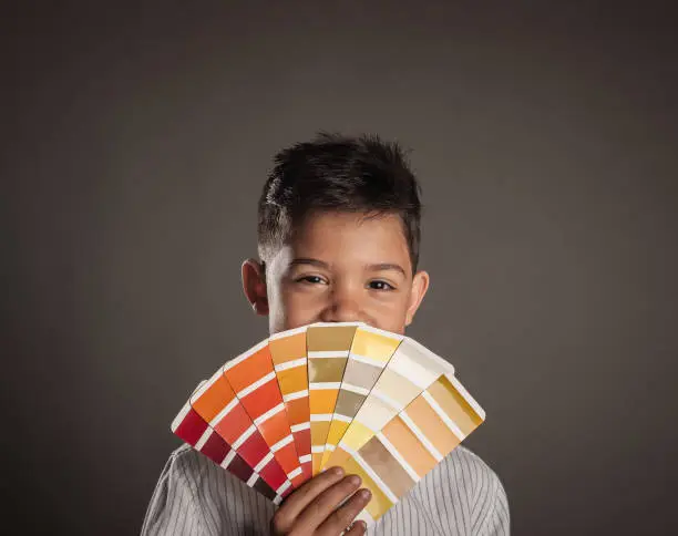 kid holding a pantone palette on a gray background