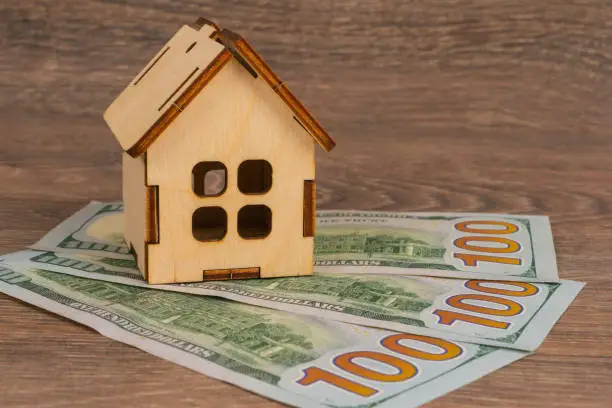 real estate concept with wooden house model and 100 dollar banknotes