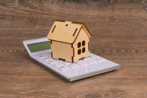 house insurance concept with wooden house model and 100 dollar banknotes