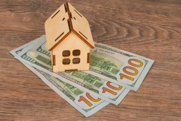 real estate concept with wooden house model and 100 dollar banknotes