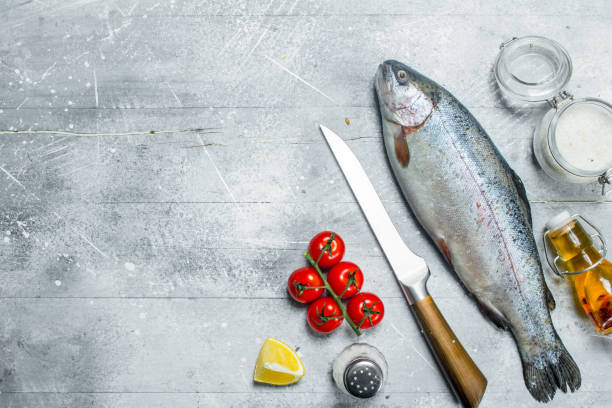 istock Raw fish salmon with spices, tomatoes and lemon. 1141700446
