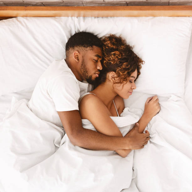 любящая пара спит в постели и обнимает - couple affectionate relaxation high angle view стоковые фото и изображения