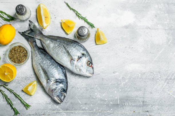istock Raw sea fish with lemon wedges and garlic. 1141703404