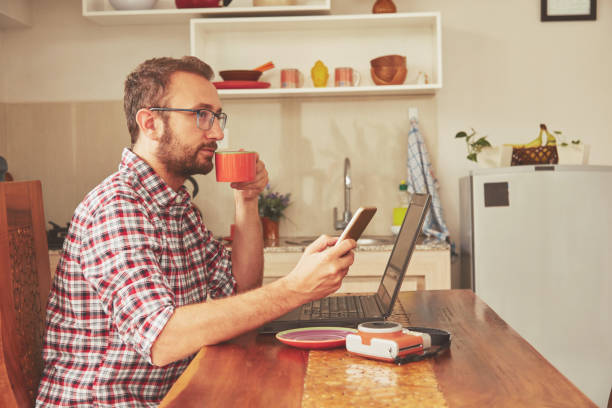 istock Modern bearded man using cellphone and drinking coffee with laptop. 1141703942