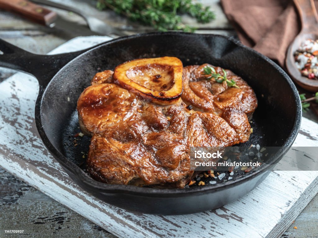 Osso buco cooked veal shank on a portion iron pan, red sauce, spices Barbecue - Meal Stock Photo