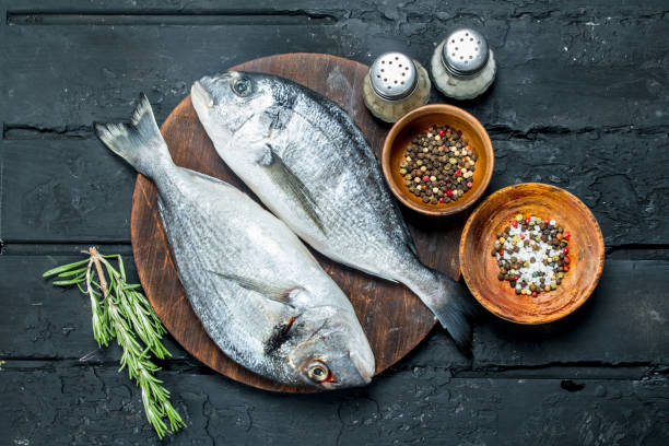 istock Raw sea fish with spices on the cutting Board. 1141709340