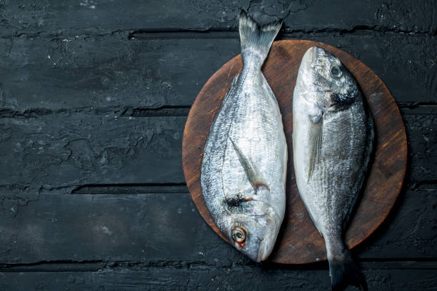 istock Raw sea fish dorado on a cutting Board. 1141709400